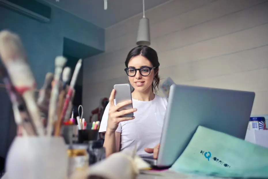 jeune femme photographiant son environnement de travail créatif avec son téléphone