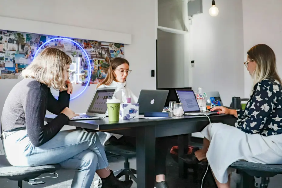 trois femmes en réunion de travail autour d'un bureau avec ordinateurs portables