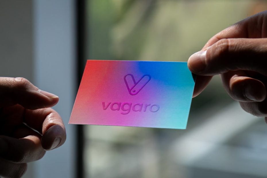 Two hands hold a colorful card with "vagaro" logo.
